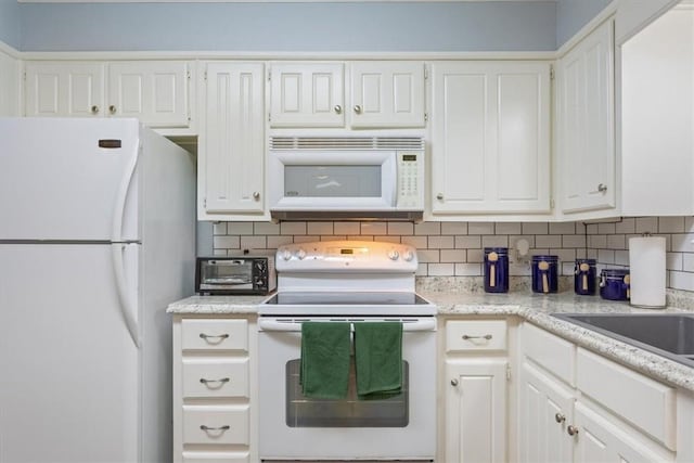 kitchen with decorative backsplash, white cabinets, and white appliances