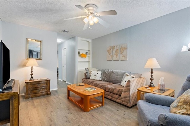 living room featuring a textured ceiling, light wood-type flooring, and ceiling fan