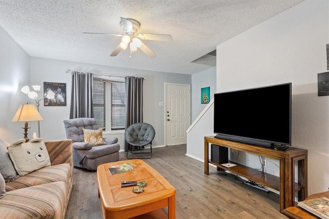 living room featuring hardwood / wood-style flooring, ceiling fan, and a textured ceiling