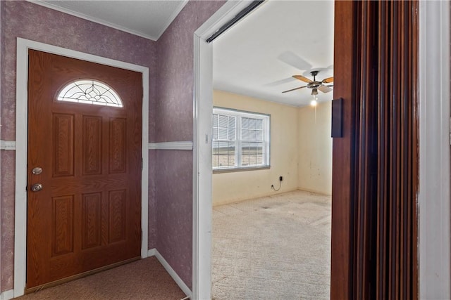 carpeted foyer with ornamental molding and ceiling fan