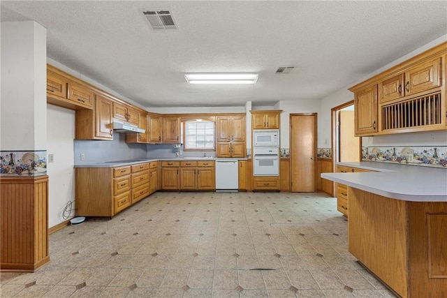 kitchen with sink, white appliances, a textured ceiling, and kitchen peninsula