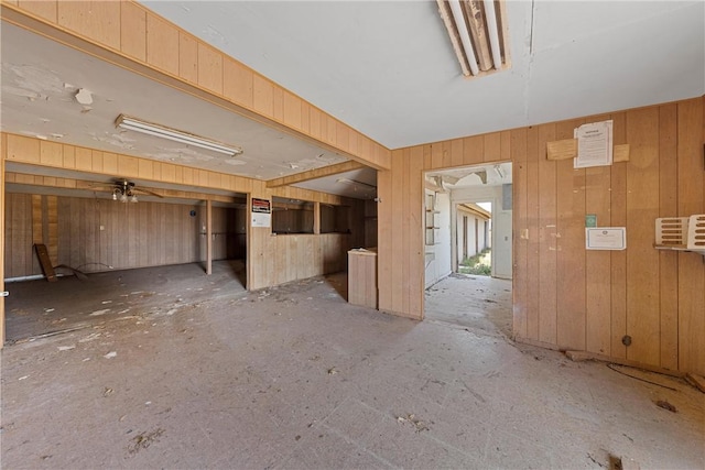 unfurnished living room with wood walls and ceiling fan