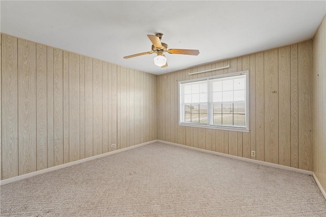 carpeted empty room with ceiling fan and wooden walls