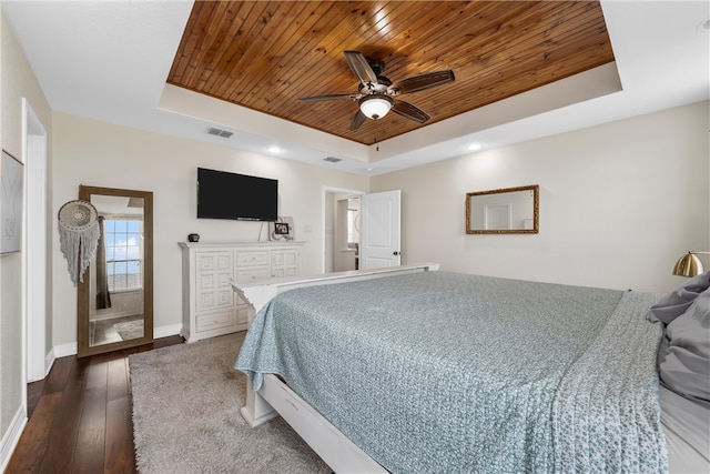 bedroom with hardwood / wood-style floors, baseboards, visible vents, a tray ceiling, and wooden ceiling