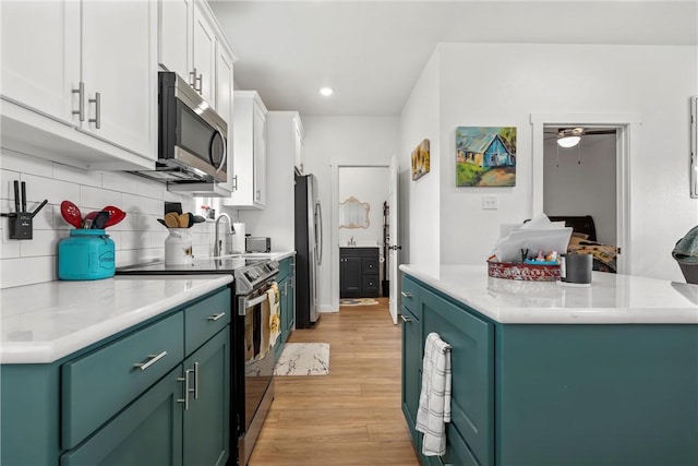 kitchen featuring light wood-style flooring, white cabinetry, stainless steel appliances, green cabinetry, and decorative backsplash