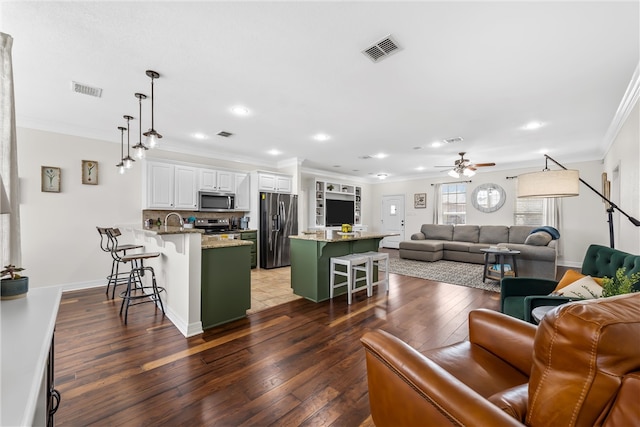 living room with visible vents, crown molding, a ceiling fan, and hardwood / wood-style flooring