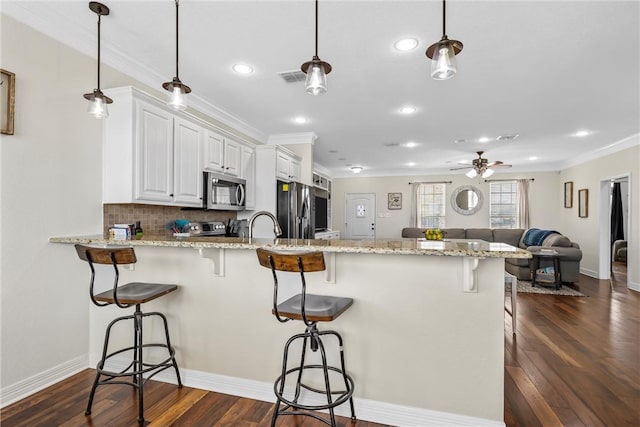 kitchen with fridge, visible vents, a peninsula, dark wood-type flooring, and stainless steel microwave