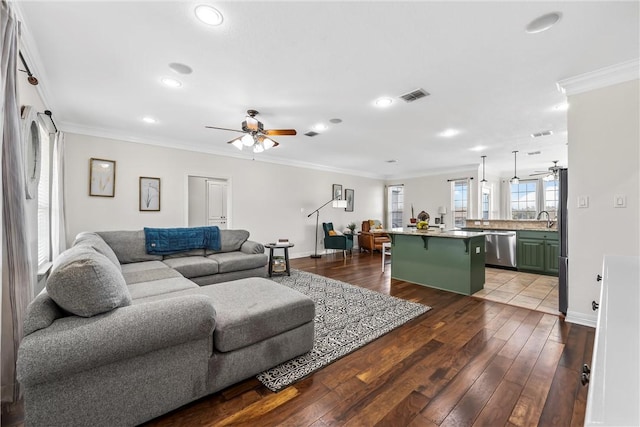 living area with dark wood finished floors, visible vents, crown molding, and ceiling fan