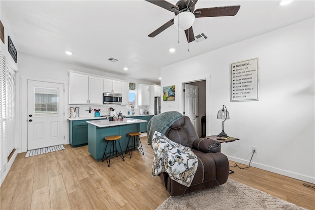 kitchen with stainless steel microwave, a kitchen island, a kitchen bar, and visible vents