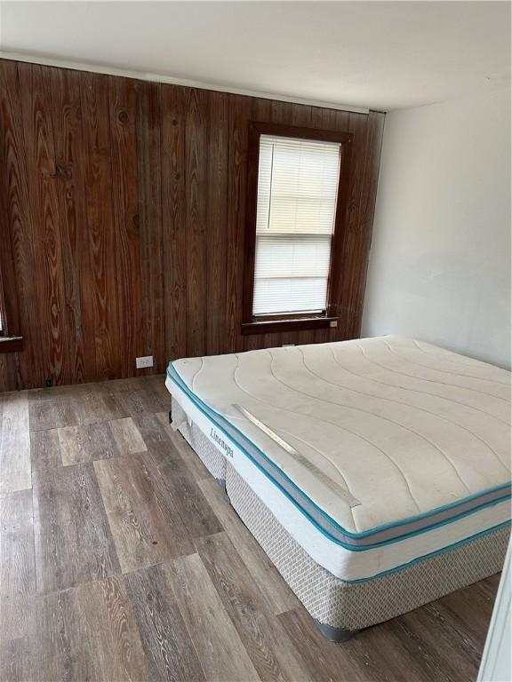 unfurnished bedroom with wood walls and wood-type flooring