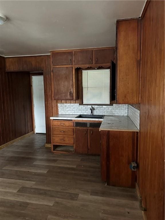 kitchen featuring backsplash, dark hardwood / wood-style flooring, sink, and wooden walls