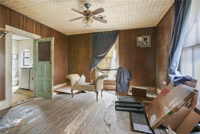 sitting room with ceiling fan, wooden walls, light hardwood / wood-style floors, and washer / clothes dryer