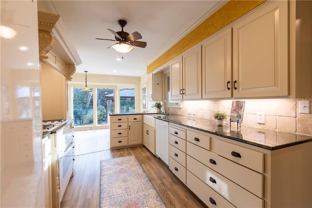 kitchen featuring dark stone countertops, backsplash, white dishwasher, decorative light fixtures, and light wood-type flooring