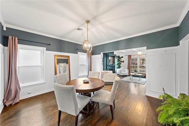 dining space with dark hardwood / wood-style floors, crown molding, and an inviting chandelier