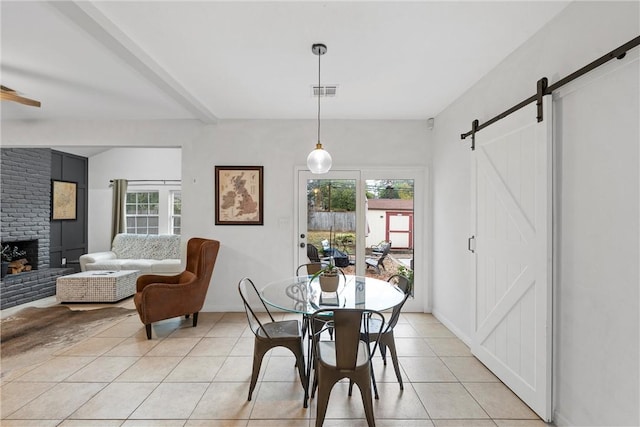 tiled dining room featuring beam ceiling, a barn door, a fireplace, and a wealth of natural light