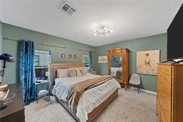 bedroom with a chandelier, light colored carpet, and a textured ceiling