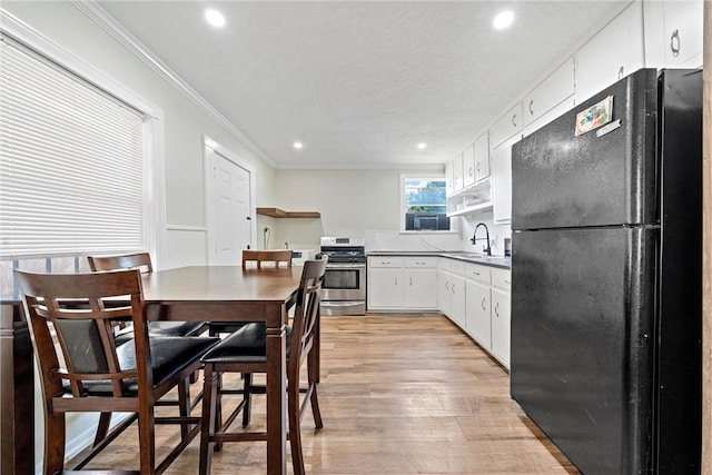 kitchen with stainless steel range, white cabinetry, black fridge, and sink