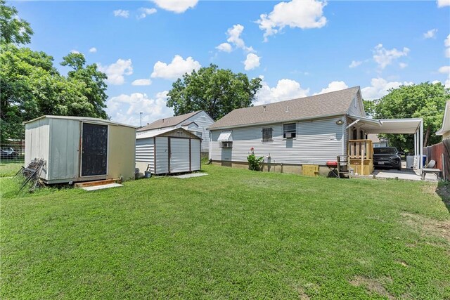 rear view of house featuring a carport, a storage unit, and a lawn