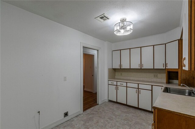 kitchen featuring sink, decorative light fixtures, a chandelier, and white cabinets