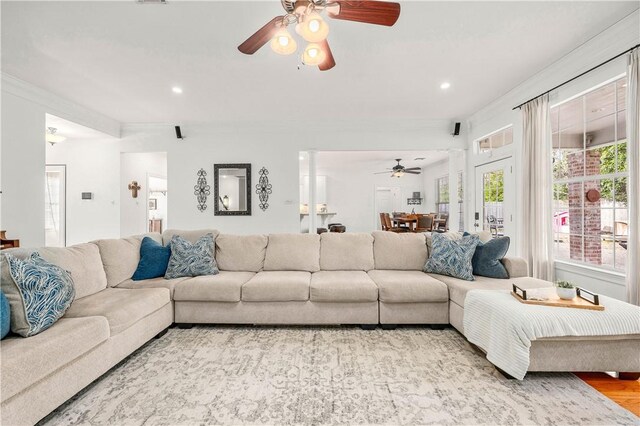 living room with crown molding, plenty of natural light, ceiling fan, and light hardwood / wood-style flooring