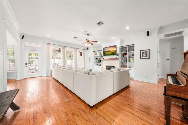 living room featuring ornamental molding, built in features, ceiling fan, and light hardwood / wood-style flooring