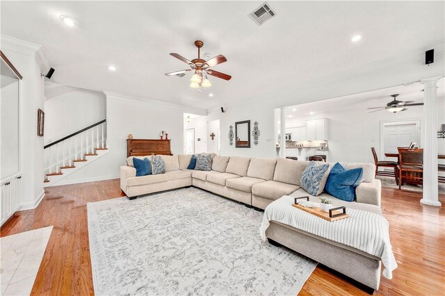 kitchen featuring white cabinets, backsplash, ornamental molding, stainless steel appliances, and light hardwood / wood-style flooring