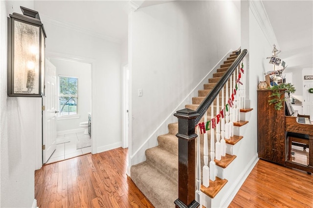 stairs with hardwood / wood-style flooring and ornamental molding