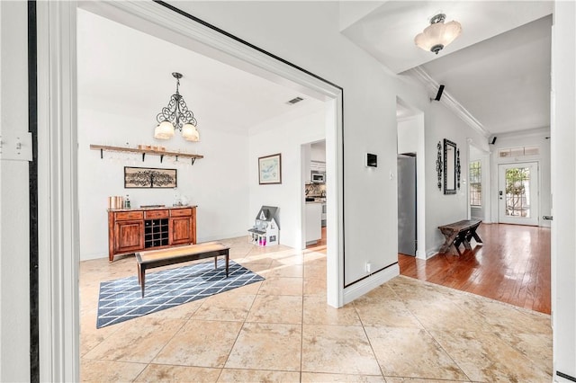 foyer entrance with crown molding, hardwood / wood-style floors, and ceiling fan with notable chandelier