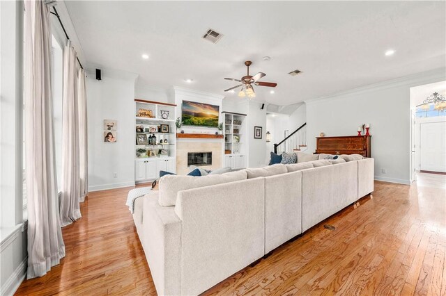 carpeted bedroom featuring a tiled fireplace, ceiling fan, and crown molding