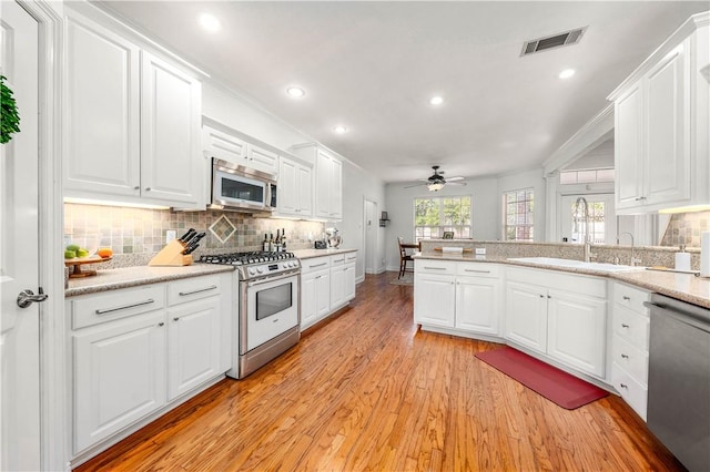 kitchen with sink, tasteful backsplash, stainless steel appliances, light hardwood / wood-style floors, and white cabinets