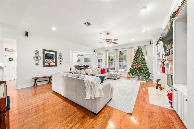 living room featuring ceiling fan, crown molding, and light hardwood / wood-style flooring