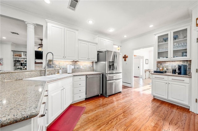 kitchen featuring sink, tasteful backsplash, stainless steel appliances, light hardwood / wood-style floors, and white cabinets