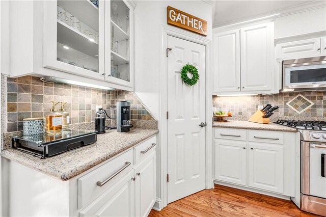 kitchen with appliances with stainless steel finishes, ceiling fan, sink, light hardwood / wood-style floors, and white cabinetry