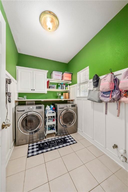 laundry room featuring cabinets, light tile patterned floors, and separate washer and dryer