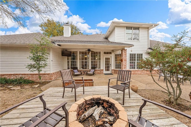 rear view of house with ceiling fan, a fire pit, and a deck