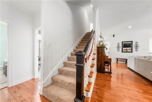 stairs featuring hardwood / wood-style floors and ornamental molding