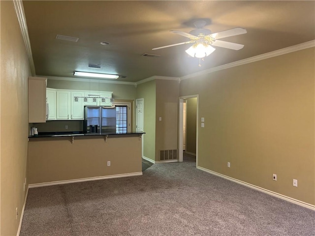 kitchen featuring white cabinets, a kitchen breakfast bar, carpet flooring, stainless steel fridge, and kitchen peninsula