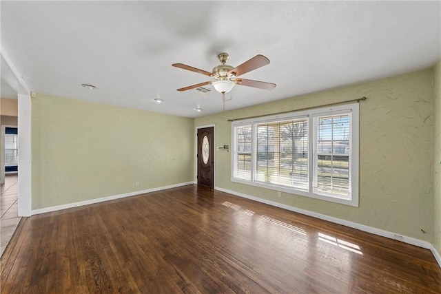 spare room featuring baseboards, visible vents, a ceiling fan, and wood finished floors