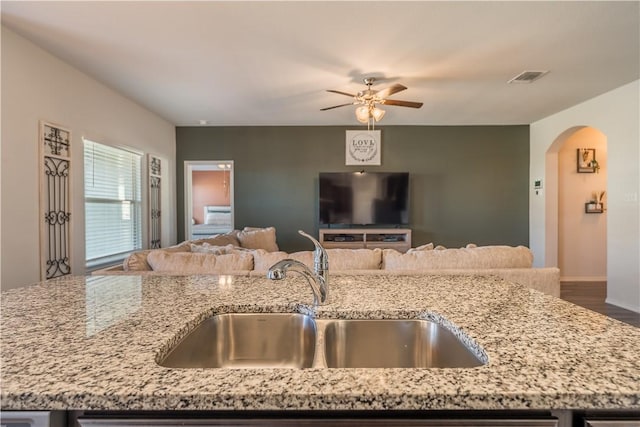 kitchen with hardwood / wood-style flooring, ceiling fan, light stone countertops, and sink