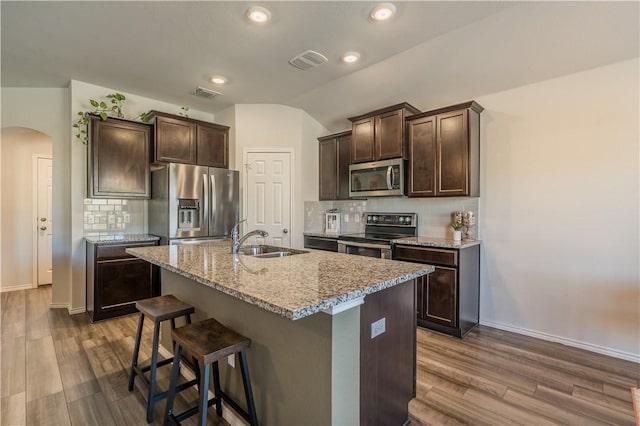 kitchen featuring stainless steel appliances, tasteful backsplash, a kitchen island with sink, and sink