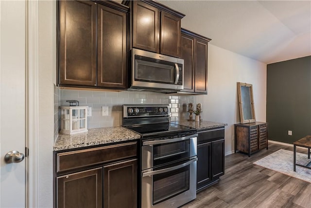 kitchen featuring dark hardwood / wood-style flooring, light stone counters, dark brown cabinets, and appliances with stainless steel finishes