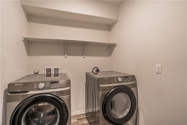 clothes washing area with washing machine and dryer and hardwood / wood-style floors