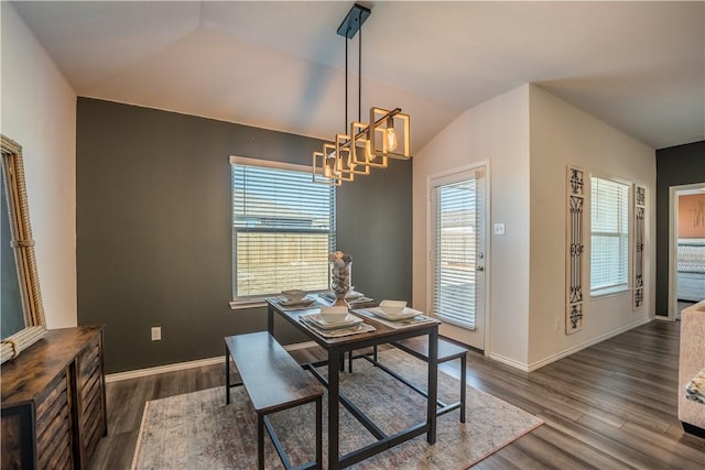 dining space with dark hardwood / wood-style flooring, vaulted ceiling, and an inviting chandelier