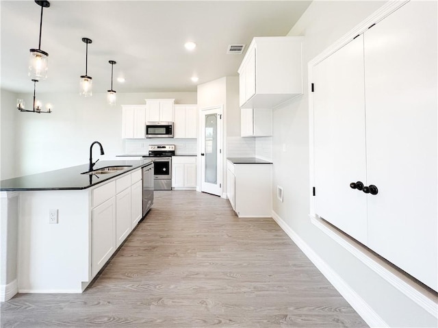 kitchen with appliances with stainless steel finishes, sink, decorative light fixtures, light hardwood / wood-style flooring, and white cabinetry