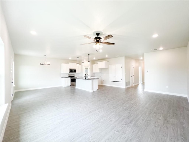 unfurnished living room with light hardwood / wood-style floors, ceiling fan, and sink