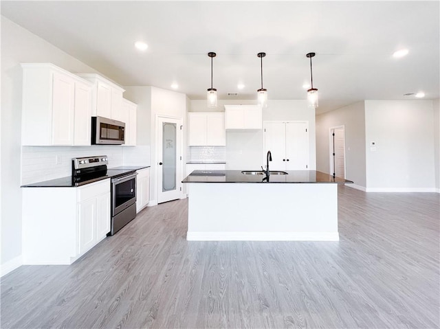 kitchen with sink, an island with sink, decorative light fixtures, white cabinetry, and stainless steel appliances