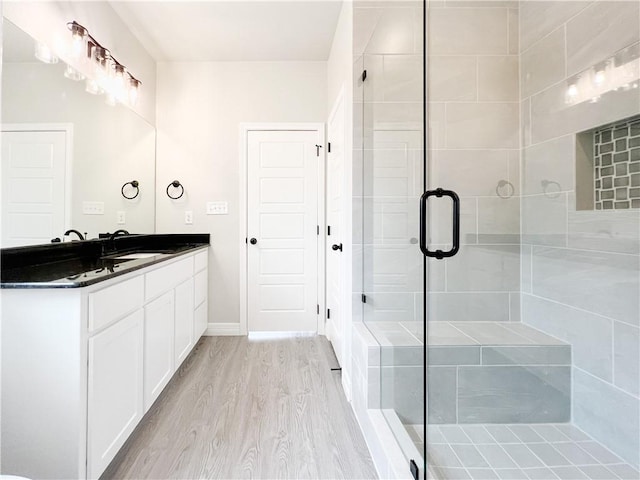 bathroom featuring hardwood / wood-style floors, vanity, and a shower with shower door