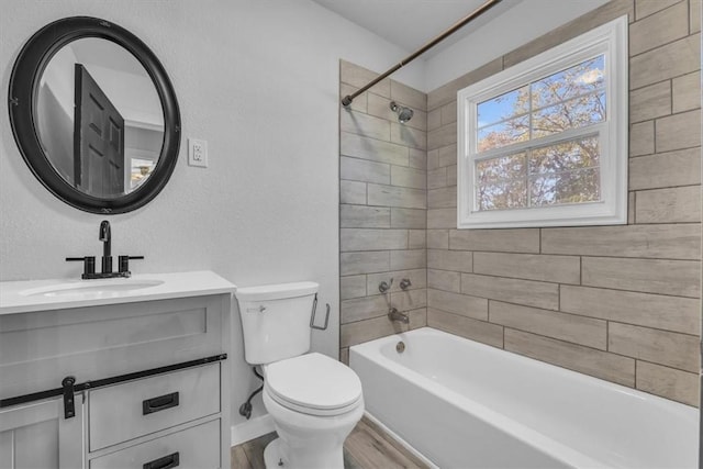 full bathroom with hardwood / wood-style floors, vanity, tiled shower / bath combo, and toilet