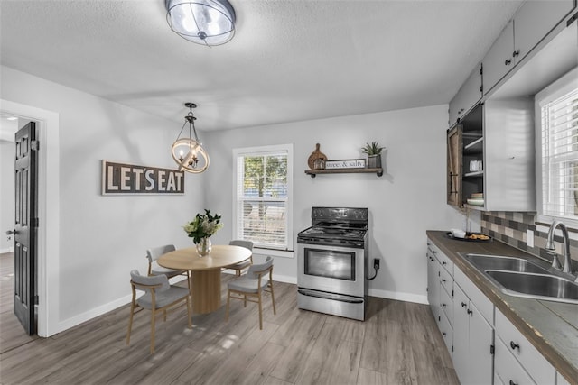 kitchen featuring a barn door, white cabinetry, a wealth of natural light, and stainless steel range oven