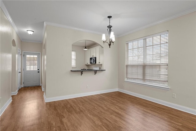 unfurnished dining area featuring crown molding, hardwood / wood-style flooring, and a chandelier